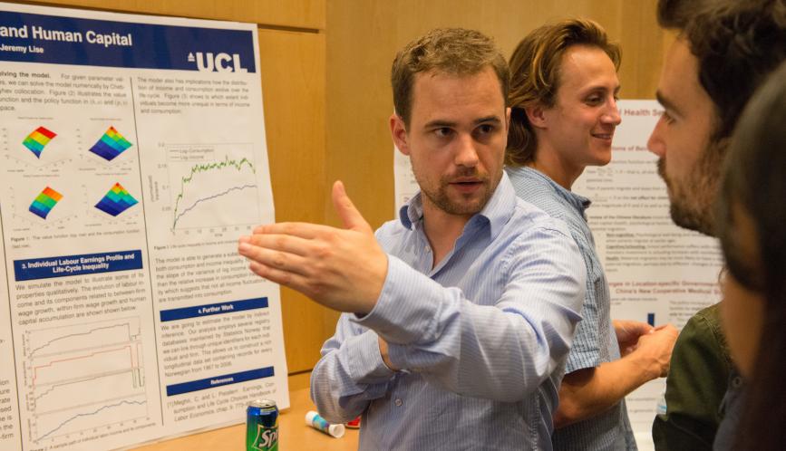 A student presents his research to another student during poster sessions.