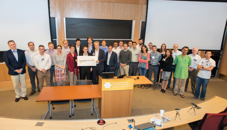 A group photo of all the conference attendees standing in front of the blackboard.