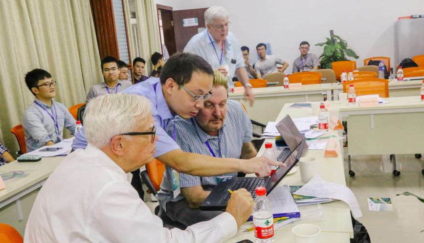 James Heckman and other conference attendees look at laptop