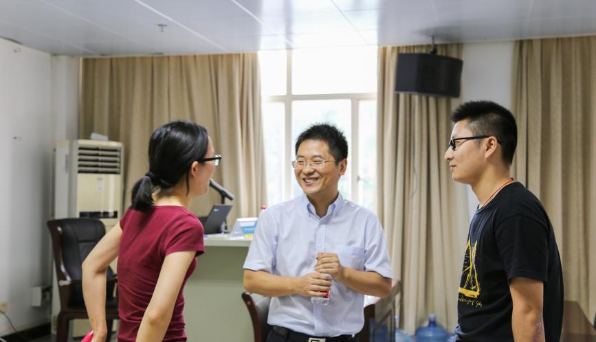 Shuaizhang Feng speaking to two students.