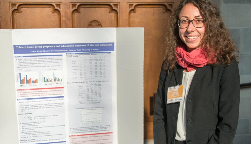 A summer school student standing in front of her research during poster sessions.
