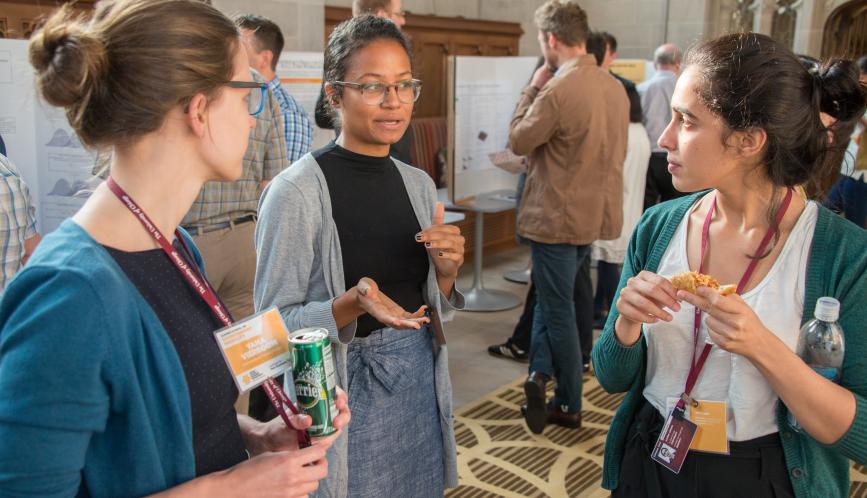 Three students stand in conversation during poster sessions.