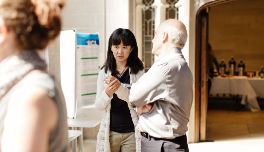 Xuejing Zuo speaks with Professor Steven Durlauf about her poster during a poster session on campus.