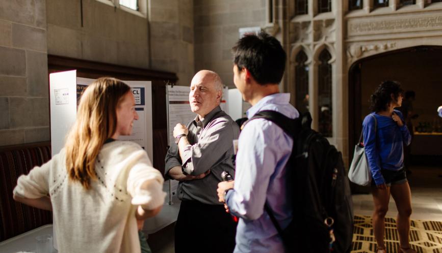 Steven Durlauf speaking to two students during poster sessions.