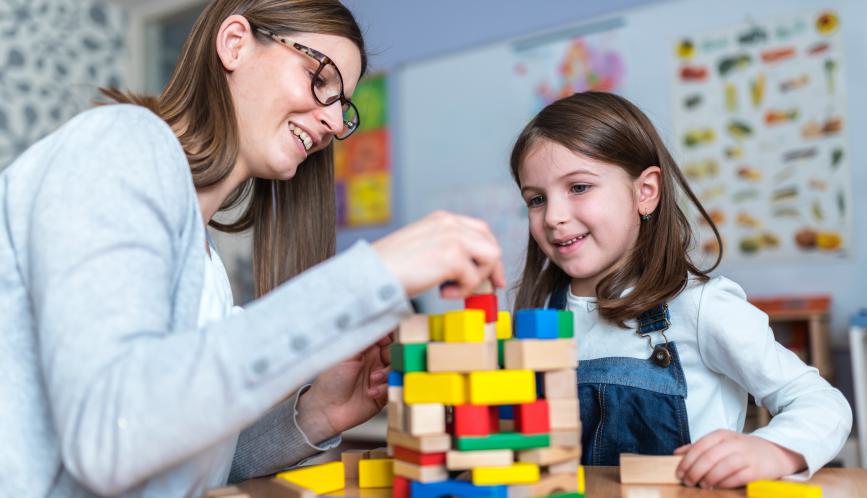 Woman and young girl playing with building blocks.