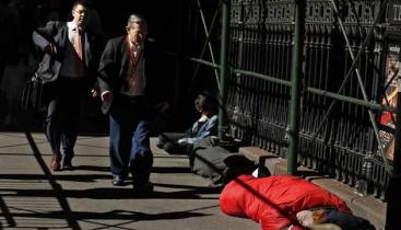 Men walking past houseless person sleeping on the street