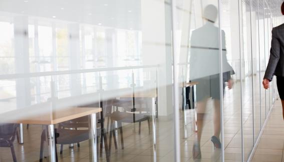 Reflection of woman wearing business attire on the window of a conference room.