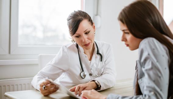 Doctor sitting with patient looking at forms.